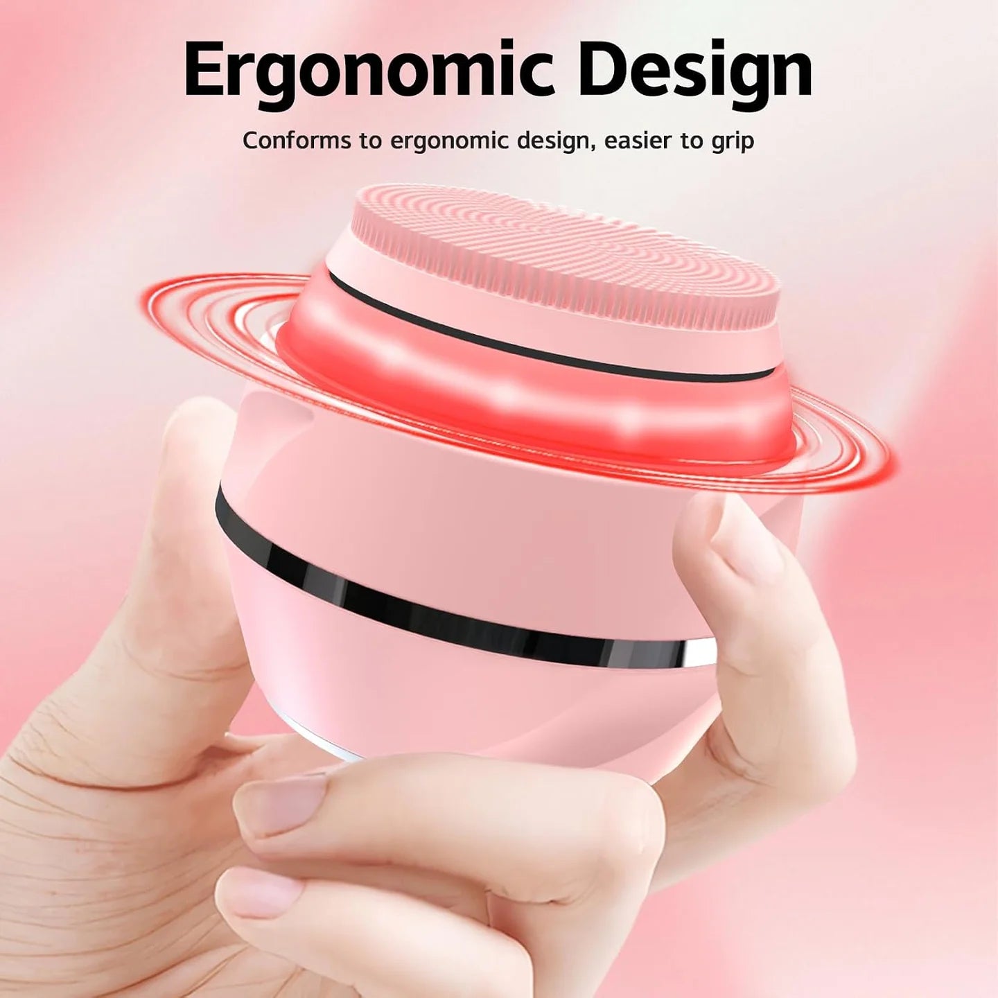 Compact pink facial cleansing brush held comfortably in one hand with its wrist loop visible